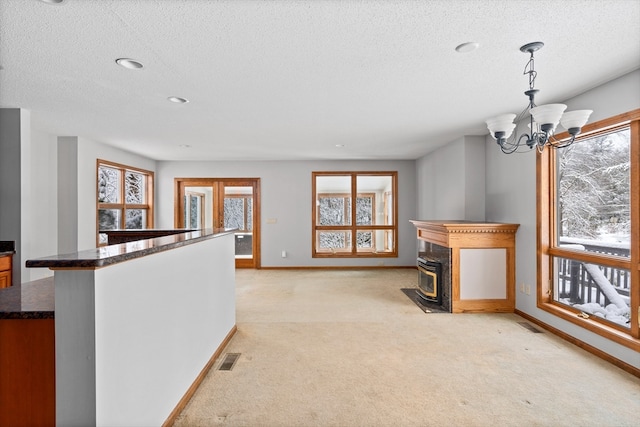 interior space featuring a textured ceiling, light colored carpet, and a chandelier