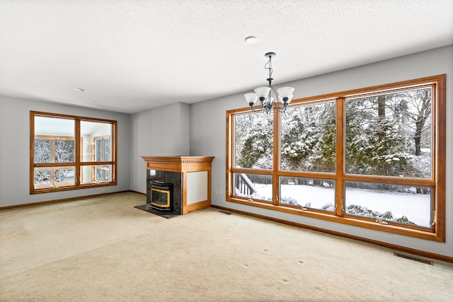 unfurnished living room with an inviting chandelier, a wealth of natural light, a high end fireplace, and light colored carpet