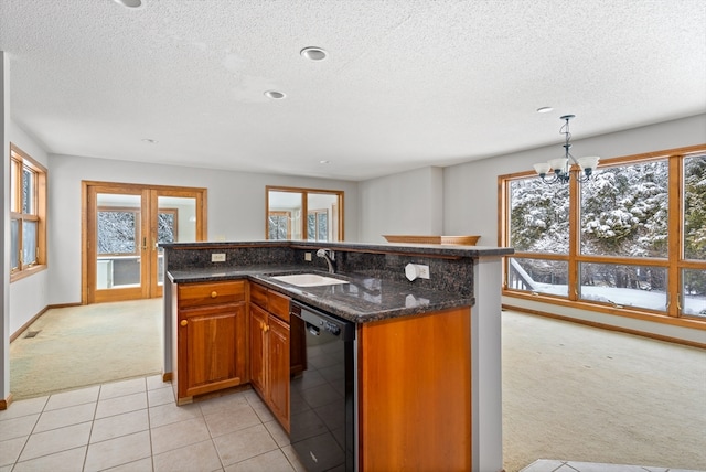 kitchen featuring an inviting chandelier, black dishwasher, dark stone countertops, sink, and light tile flooring