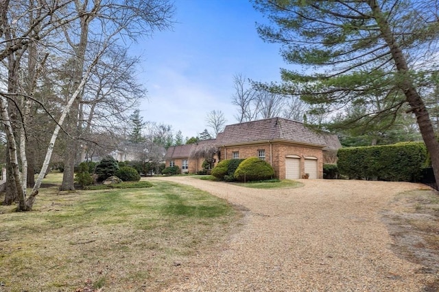 21 Wildewood Dr, Lynnfield, MA 01940 - view of side of home featuring mansard roof, dirt driveway, an attached garage, brick siding, and a yard