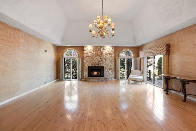 21 Wildewood Dr, Lynnfield, MA 01940 - unfurnished living room featuring a stone fireplace, hardwood / wood-style flooring, an inviting chandelier, and a healthy amount of sunlight
