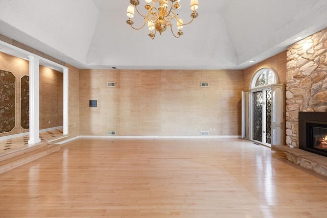 21 Wildewood Dr, Lynnfield, MA 01940 - unfurnished living room featuring a fireplace, visible vents, wood finished floors, lofted ceiling, and a notable chandelier