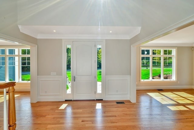 foyer entrance with plenty of natural light, crown molding, and light wood-type flooring