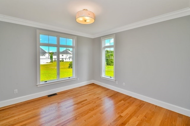 spare room with ornamental molding and light hardwood / wood-style floors