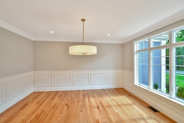 unfurnished dining area featuring ornamental molding and light wood-type flooring