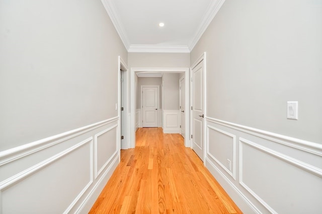 hall with light hardwood / wood-style floors and ornamental molding