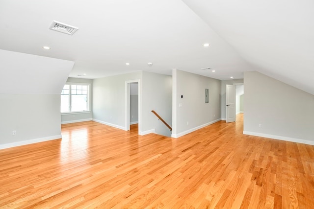 additional living space with light hardwood / wood-style floors and lofted ceiling