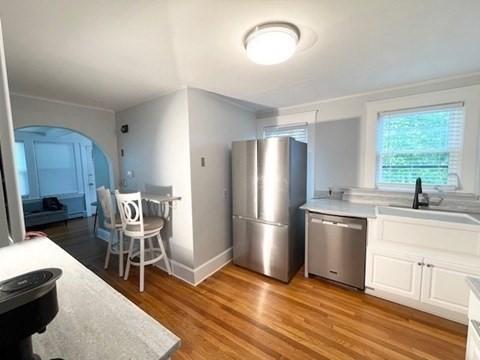 192 Salem St, Wakefield, MA 01880 - kitchen with stainless steel appliances, arched walkways, white cabinetry, light wood-type flooring, and light countertops