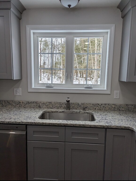 kitchen featuring gray cabinetry, sink, and stainless steel dishwasher