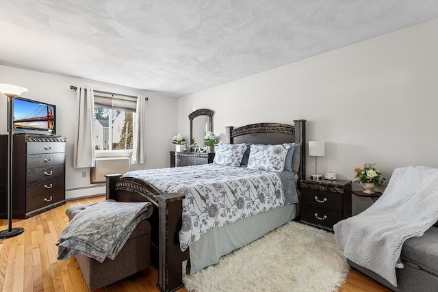 bedroom featuring baseboard heating, a textured ceiling, and hardwood / wood-style floors