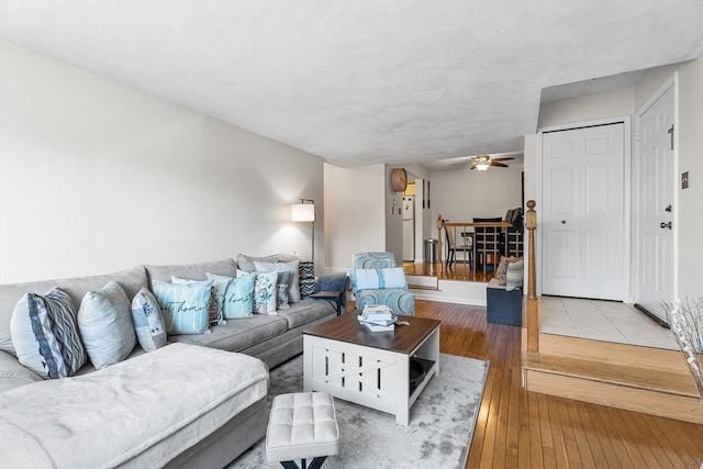 living room featuring light wood-type flooring, baseboards, and ceiling fan