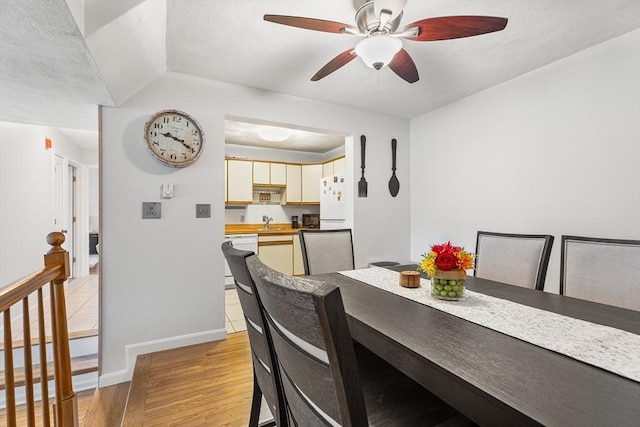 dining area featuring a textured ceiling, light wood-style floors, baseboards, and ceiling fan