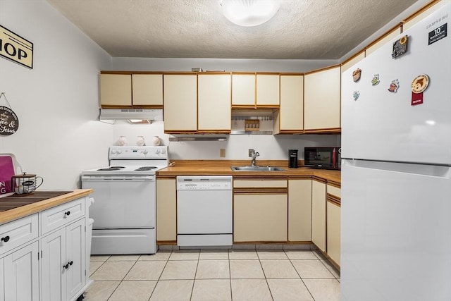 kitchen featuring a sink, under cabinet range hood, a textured ceiling, white appliances, and light tile patterned floors