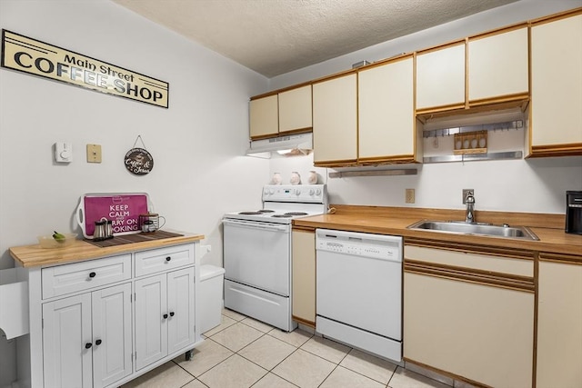 kitchen featuring a sink, under cabinet range hood, a textured ceiling, white appliances, and light tile patterned flooring