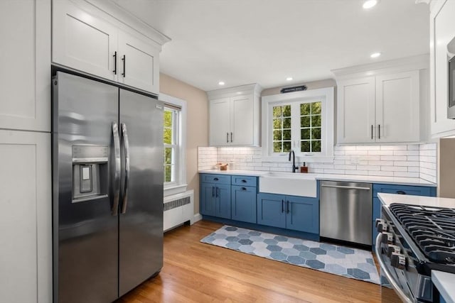 kitchen featuring stainless steel appliances, radiator heating unit, a sink, plenty of natural light, and recessed lighting