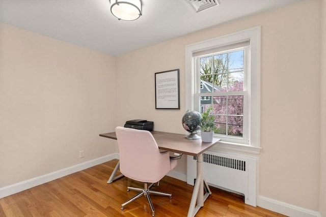 home office with radiator, light wood finished floors, and baseboards