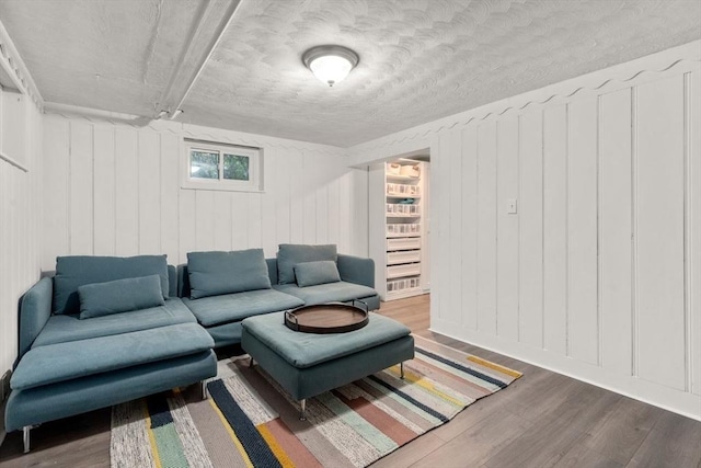 living area with wood finished floors, a decorative wall, and a textured ceiling