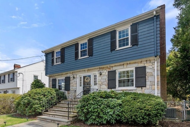 view of front of home with stone siding and fence