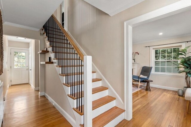 staircase with wood-type flooring, crown molding, and baseboards