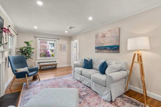 living area with crown molding, baseboards, recessed lighting, wood finished floors, and radiator heating unit