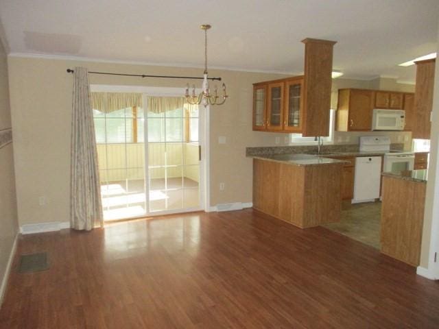 kitchen with dark hardwood / wood-style floors, white appliances, crown molding, and an inviting chandelier