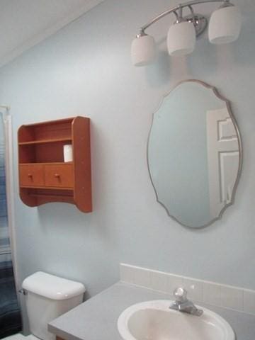 bathroom with walk in shower, vanity, vaulted ceiling, and toilet