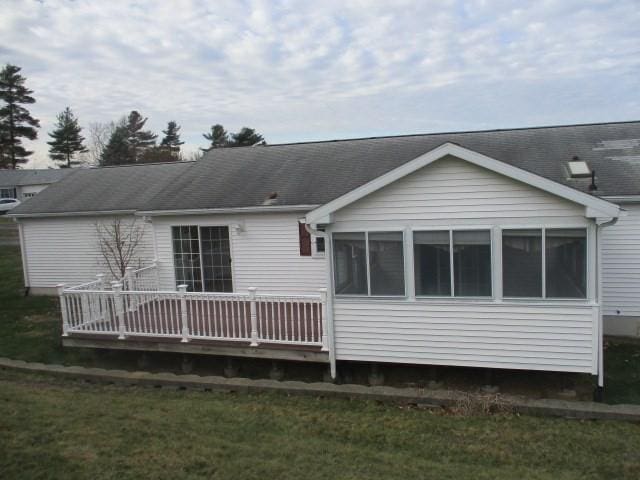 back of house with a wooden deck, a sunroom, and a yard