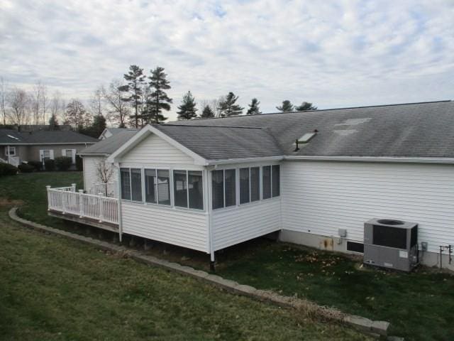 back of house featuring a yard, a sunroom, and central air condition unit