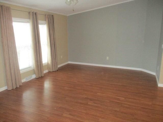 spare room featuring dark hardwood / wood-style flooring, crown molding, and a healthy amount of sunlight