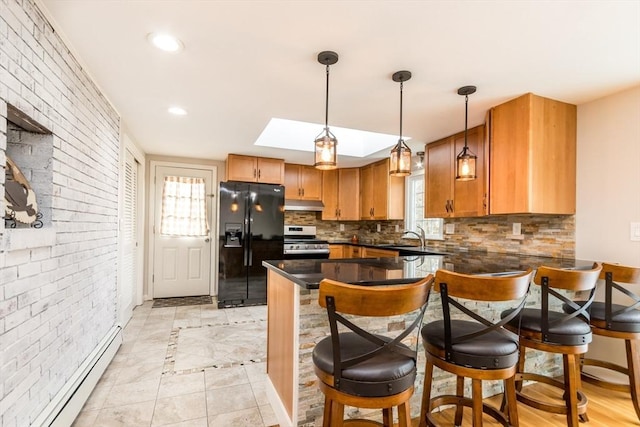 kitchen featuring a skylight, black refrigerator with ice dispenser, a baseboard heating unit, pendant lighting, and stainless steel stove