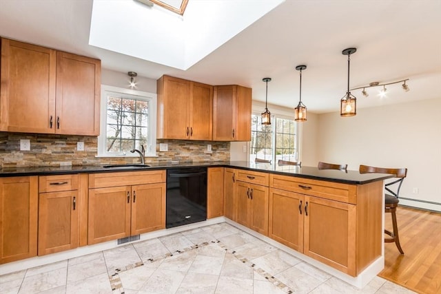 kitchen featuring kitchen peninsula, a skylight, sink, dishwasher, and hanging light fixtures