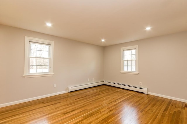 empty room featuring light hardwood / wood-style floors, a wealth of natural light, and a baseboard radiator