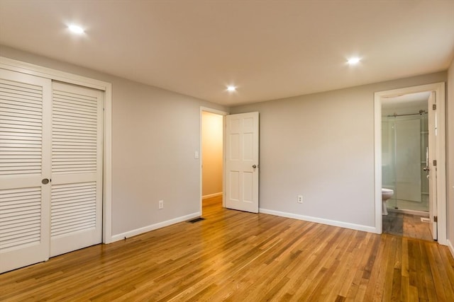 unfurnished bedroom featuring connected bathroom, a closet, and light hardwood / wood-style floors