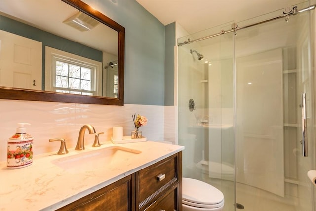 bathroom featuring vanity, tasteful backsplash, toilet, and walk in shower