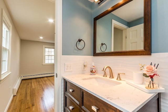 bathroom with vanity, wood-type flooring, backsplash, and a baseboard heating unit