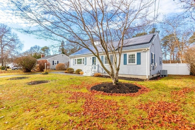 view of front of house featuring central air condition unit, a front yard, and solar panels