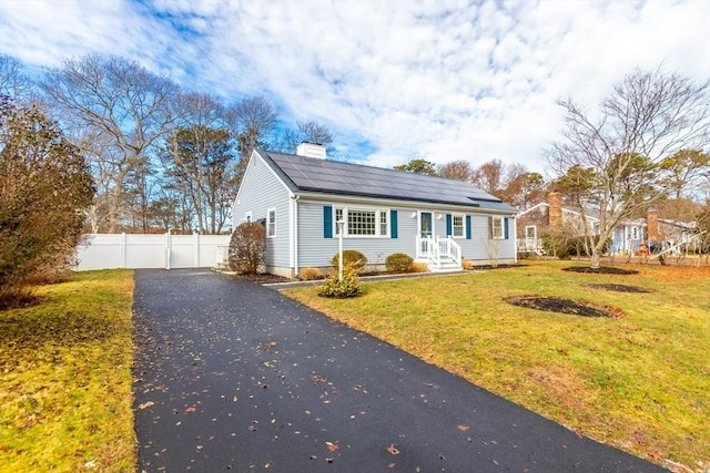 view of front of house featuring solar panels and a front lawn