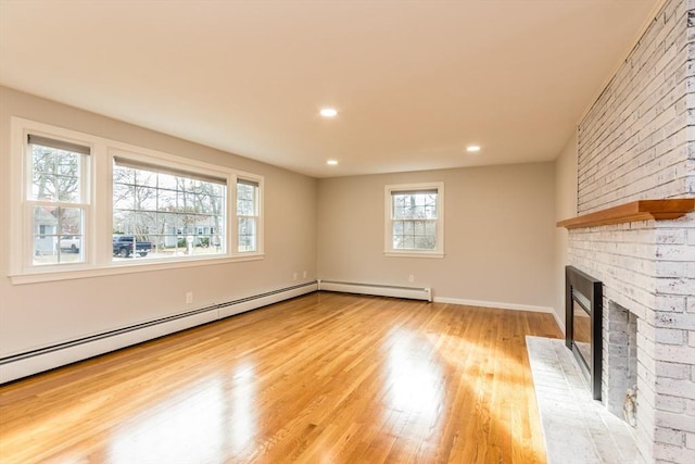 unfurnished living room with light wood-type flooring, a baseboard heating unit, and a brick fireplace