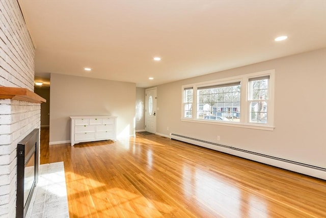 unfurnished living room with a fireplace, light wood-type flooring, and a baseboard radiator