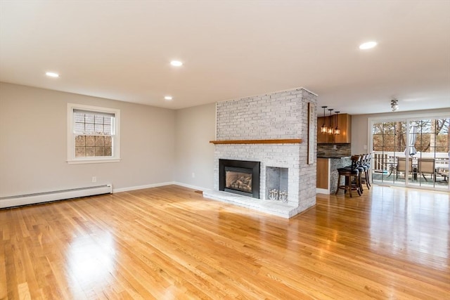 unfurnished living room with a fireplace, light hardwood / wood-style floors, and a baseboard radiator