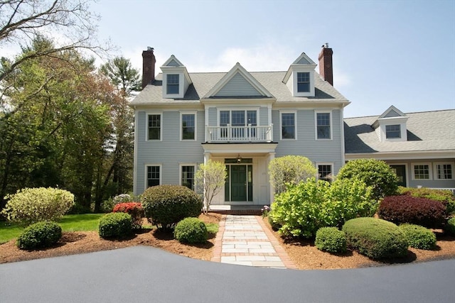 view of front of house featuring a chimney and a balcony