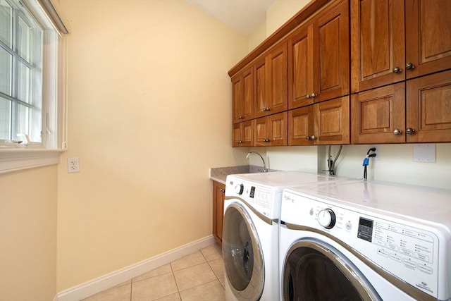 clothes washing area with light tile patterned floors, a sink, baseboards, independent washer and dryer, and cabinet space