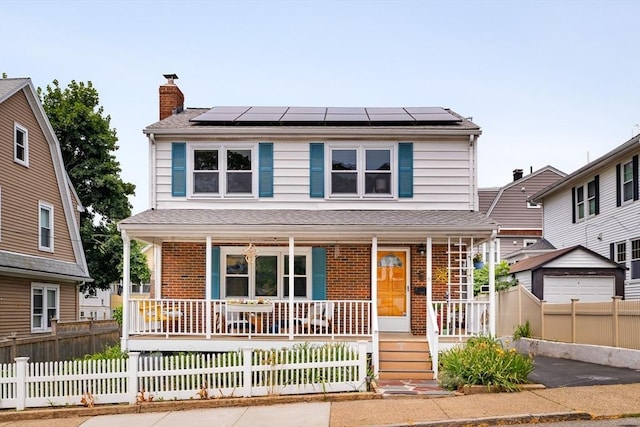 51 Burget Ave, Medford, MA 02155 - view of front of house featuring covered porch, a chimney, roof mounted solar panels, and brick siding