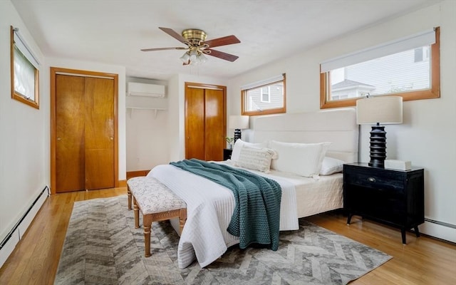 51 Burget Ave, Medford, MA 02155 - bedroom with a baseboard radiator, a wall unit AC, light wood-style flooring, and multiple closets