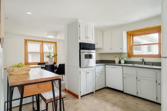 51 Burget Ave, Medford, MA 02155 - kitchen featuring dishwasher, oven, a sink, white cabinets, and a baseboard radiator
