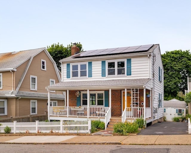 51 Burget Ave, Medford, MA 02155 - view of front facade featuring covered porch, a chimney, solar panels, and brick siding