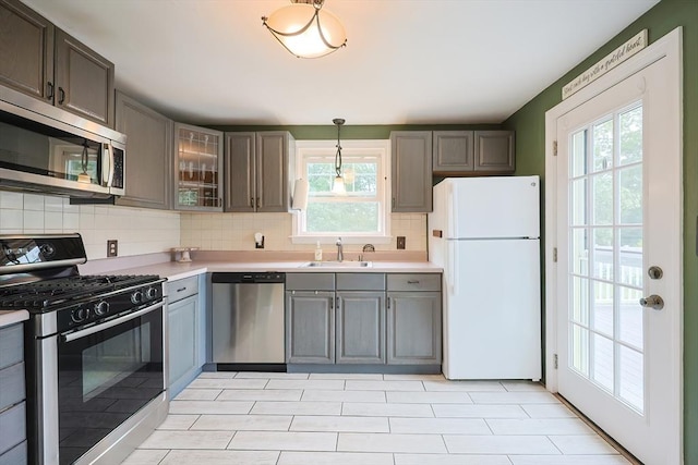57 Hawes St, Wrentham, MA 02093 - kitchen featuring stainless steel appliances, backsplash, light countertops, glass insert cabinets, and decorative light fixtures
