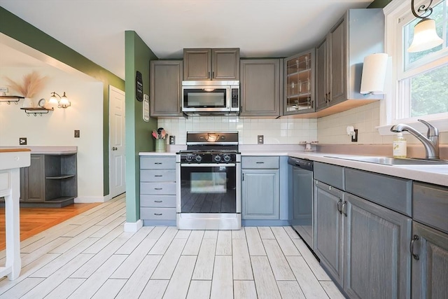 57 Hawes St, Wrentham, MA 02093 - kitchen featuring stainless steel appliances, gray cabinetry, light wood-style flooring, decorative backsplash, and light countertops