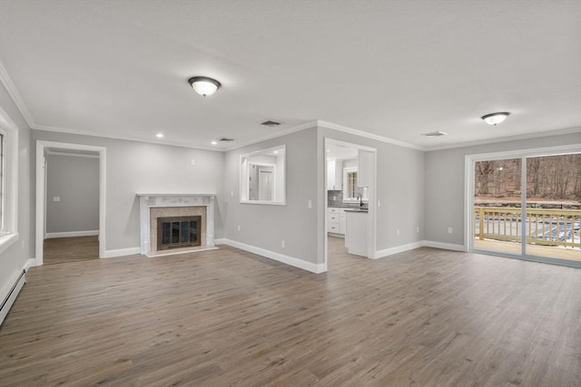 unfurnished living room with hardwood / wood-style flooring, ornamental molding, a premium fireplace, and sink