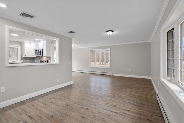 unfurnished living room with a wealth of natural light, ornamental molding, and baseboard heating